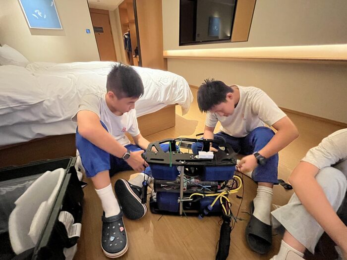 Two students repairing the ROV in their hotel room at night