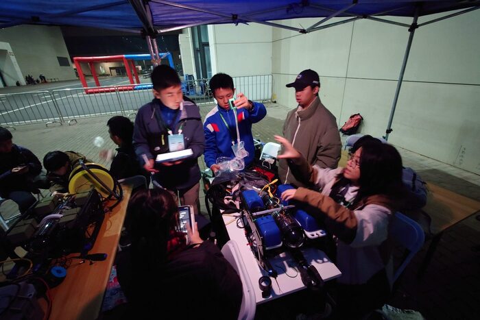 Students working on vehicles in the pit tent before a run